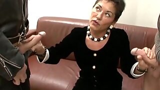 Mature in her work clothes strokes two dicks